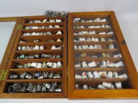 Large selection of various ceramic and pewter and ceramic thimbles in 2 glass display cases.