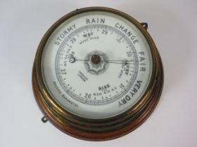 Enamel faced brass barometer on wooden mount approx 10" diameter.