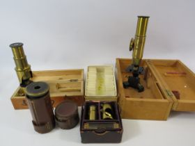 Various vintage brass small medical microscopes and a small selection of slides.