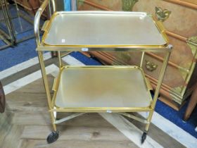 Late 20th Century gold tone metal two tier serving trolley with detachable trays. Runs on smooth cas