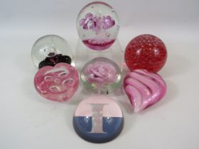 7 Pink, red coloured Paperweights.