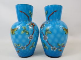 Pair of cased art glass blue vases hand painted with flowers and butterflies. Approx 7.5" tall.