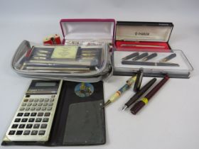 Selection of various pens and a vintage casio calculator.