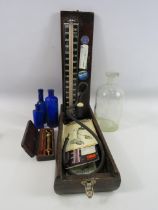 Vintage blood pressure monitor, gold coloured metal syringe and vintage medical bottles.