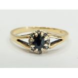 9ct Yellow Gold ring set with a central Sapphire with large claw mounts and surrounded by small Mele