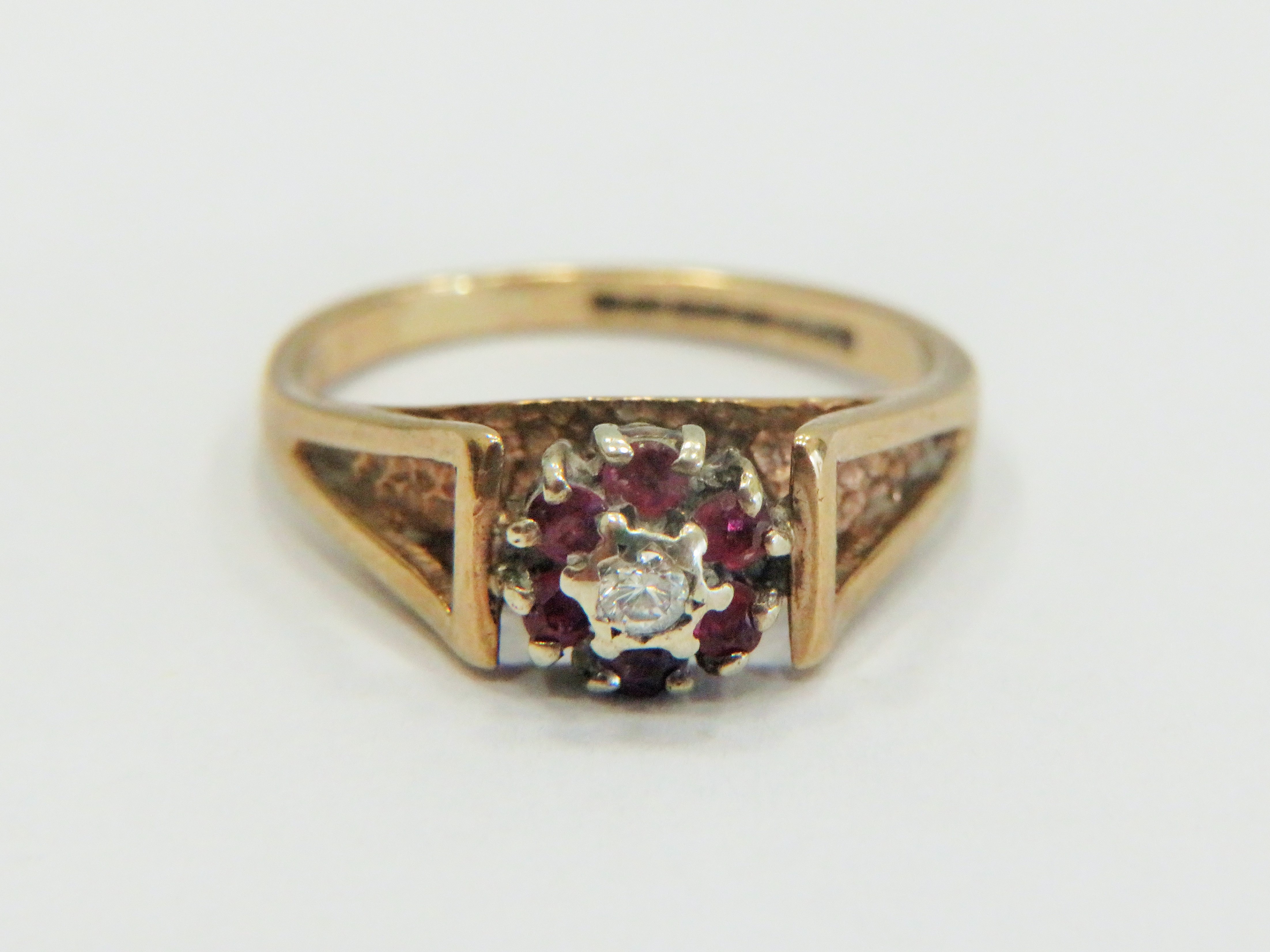 9ct Yellow Gold Ring set with a small central Diamond, surrounded by small Rubies. Small finger size