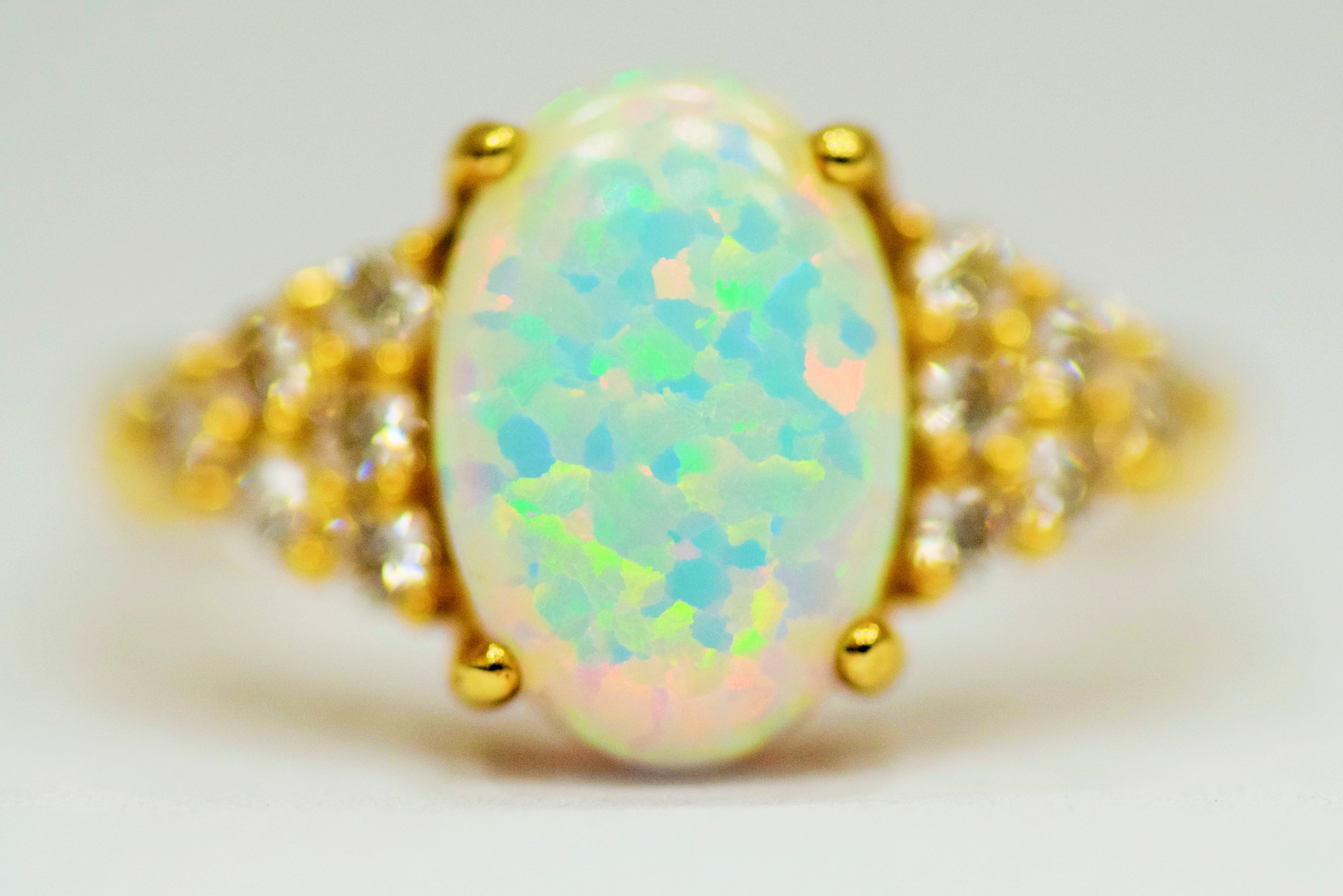 14ct Yellow Gold Ring set with a large central Opal which measures 12 x 8mm with 12 clear gemstones 