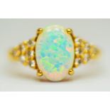 14ct Yellow Gold Ring set with a large central Opal which measures 12 x 8mm with 12 clear gemstones 