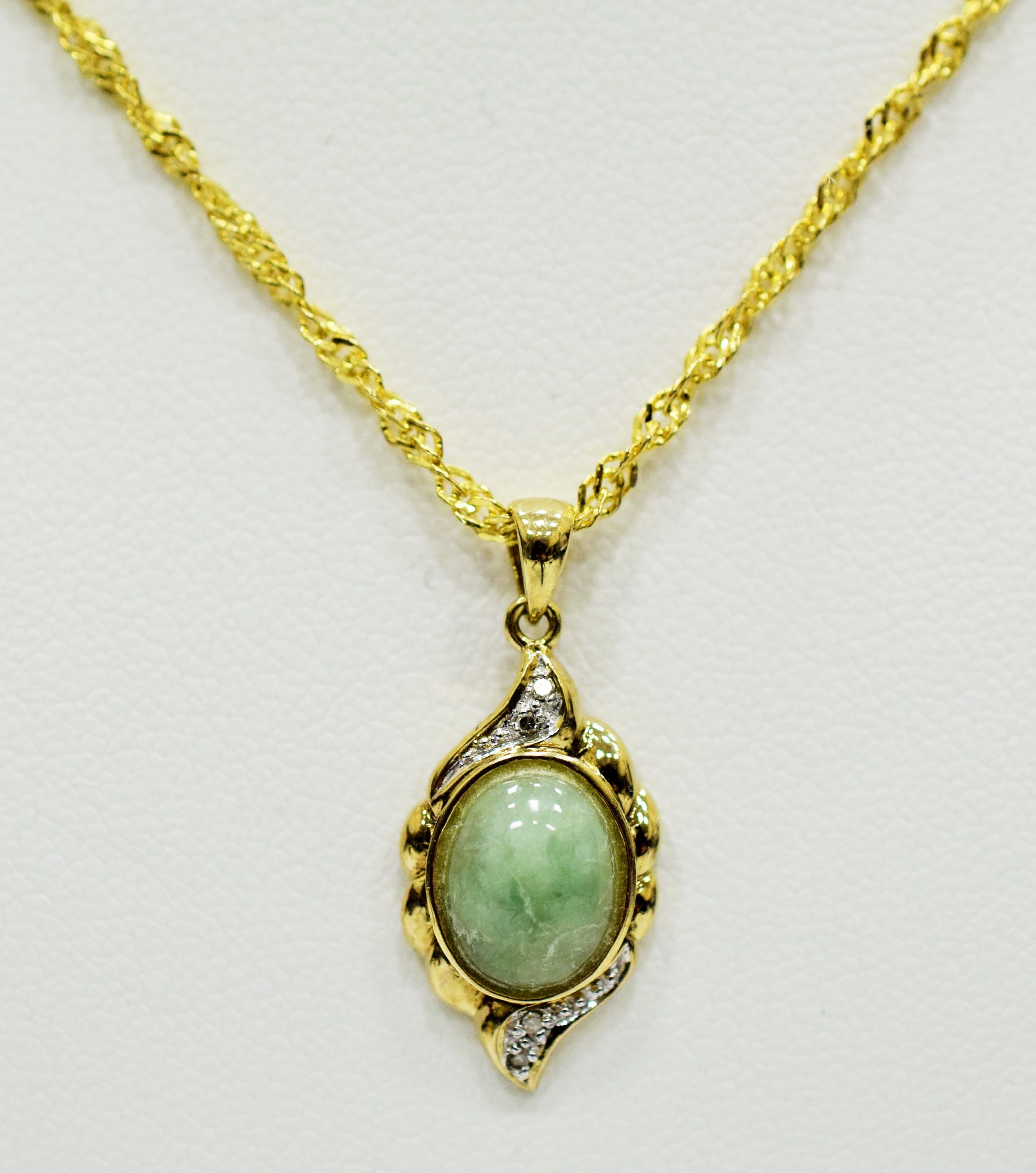 9ct Yellow Gold Pendant set with a Central Jade with Diamond surround. Hung on a 14ct fancy link 22 