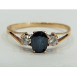9ct Gold ring set with a Central Sapphire supported by small CZ gemstones to each side.  Finger size
