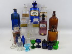 Large selection of various coloured vintage medical bottles and eye wash baths.