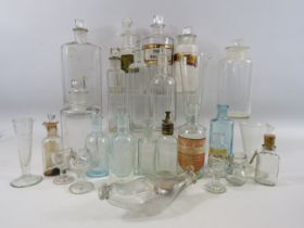 Large selection of vintage clear glass medicine bottles, measures and eye wash baths.