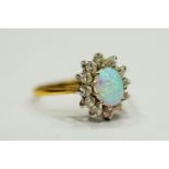 9ct Yellow Gold ring set with a lovely Central Opal which measures 8 x 5mm, surrounded by Clear gems