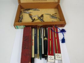 Wooden cigar box containing various pens and nibs.