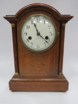 Oak cased enamel faced mantle clock approx 13" tall, running but does require a key.