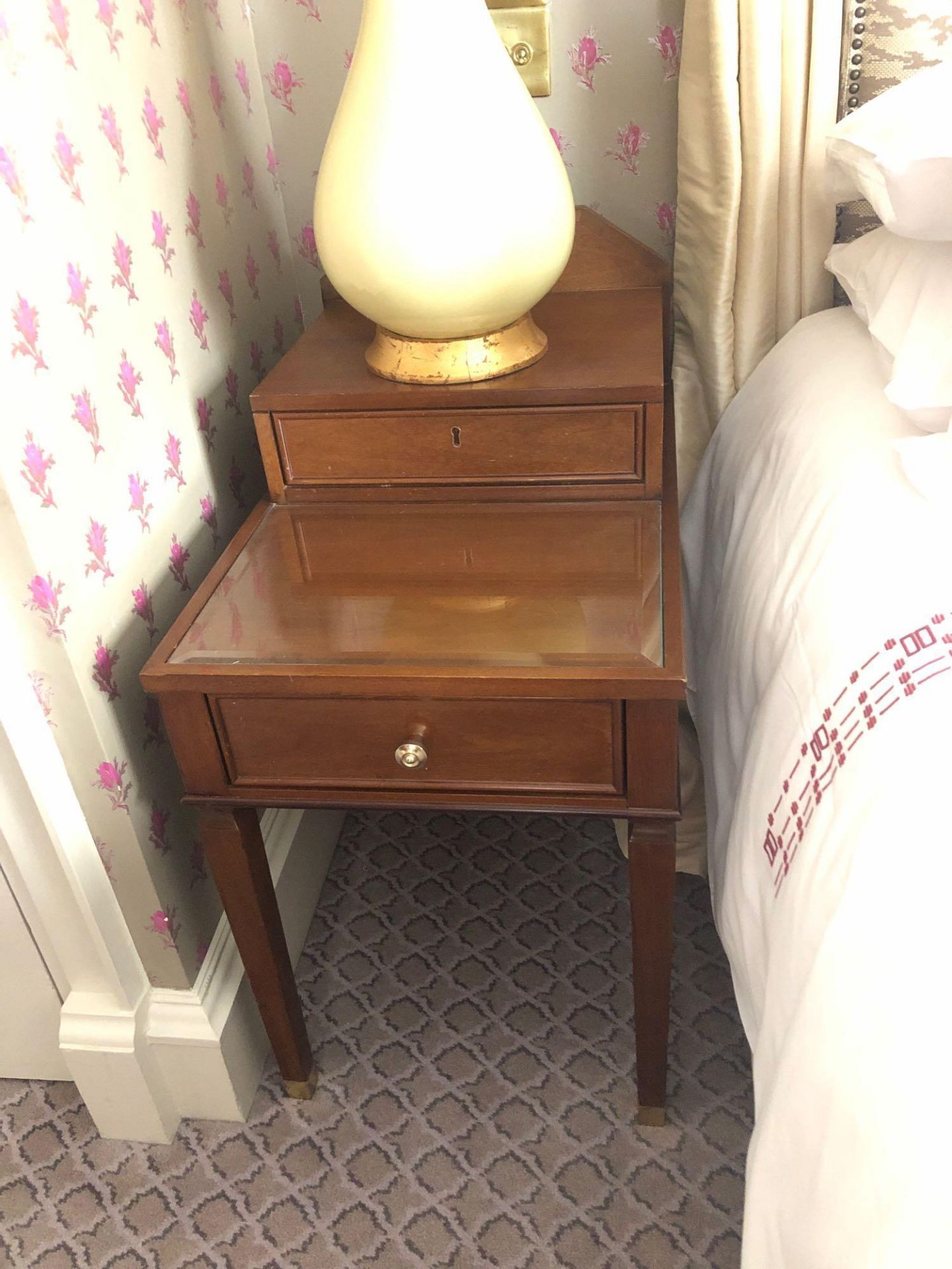 A Pair Of Two Tier Bedside Nightstands With Storage Compartments Mounted On Tapered Legs With