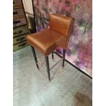 A pair of leather bar stools with sleek black wood legs with metal foot bar/side bars and foot
