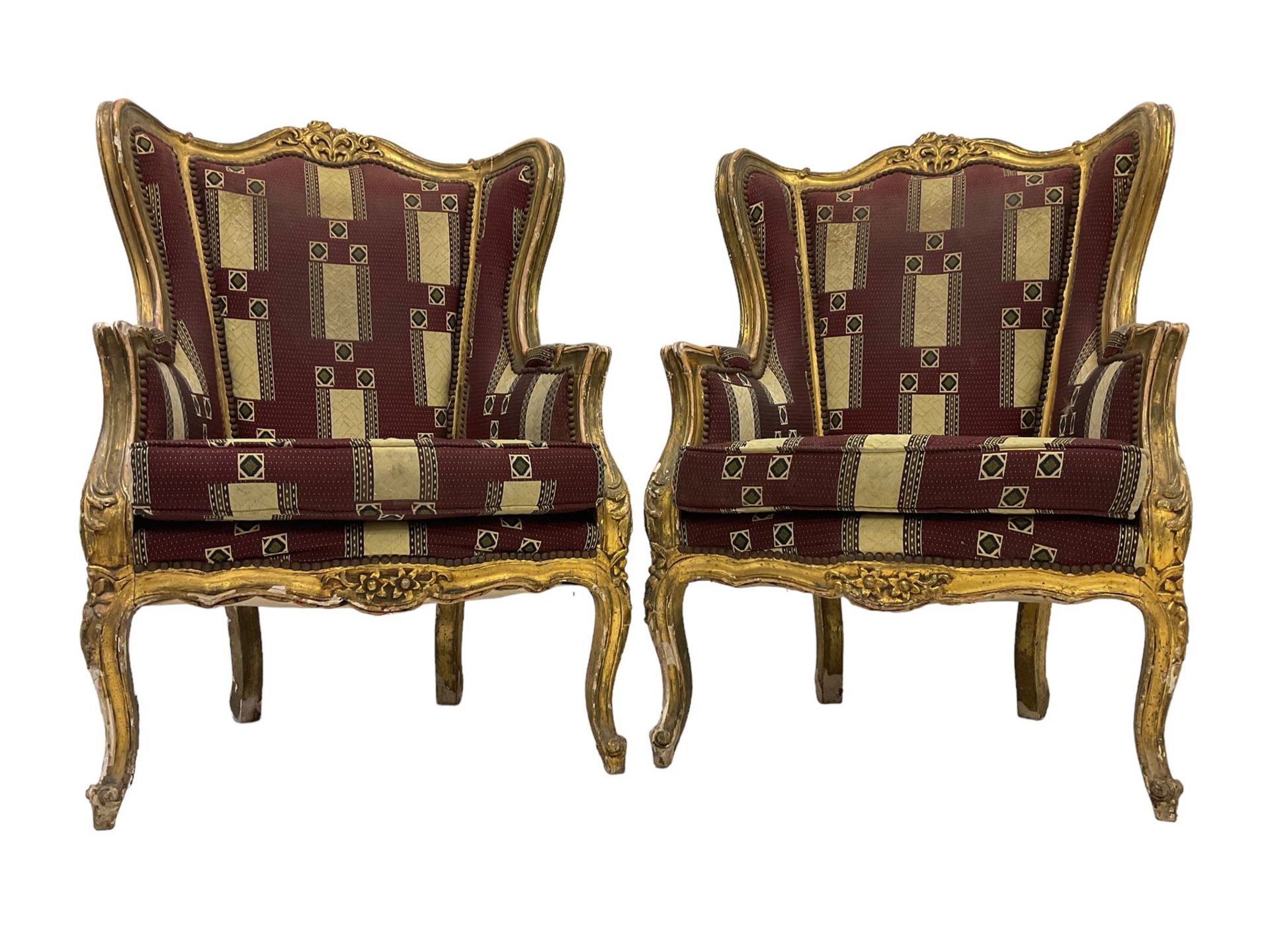 A Pair Louis XV design gilt framed wingback armchairs, the cresting rail carved and moulded with a