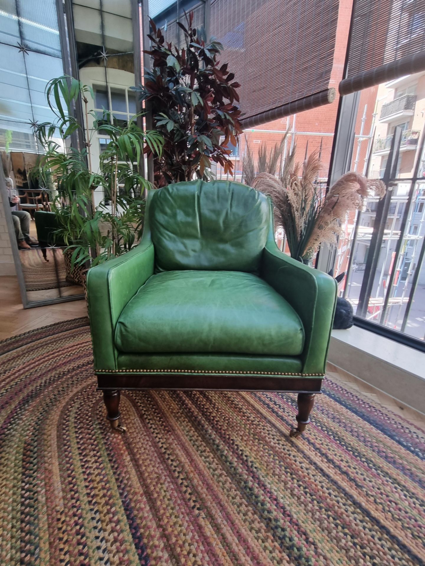 A  Green Leather upholstered vintage armchair on castor front legs reupholstered in a racing green