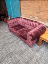 A pair of Chesterfield style fabric sofas with classic rolled arms and tufted profile upholstered in