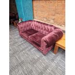 A pair of Chesterfield style fabric sofas with classic rolled arms and tufted profile upholstered in