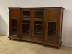 An Edwardian mahogany inverted break front bookcase, the centre twin doors enclosing three