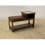 A mid century telephone table, with glass top and open shelf flanking a faux leather upholstered
