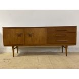 A mid century teak sideboard, the concave front with three drawers flanked by a fall front