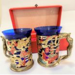 A pair of gilt metal Japanese enamelled cup holders with blue glass liners with Buddha and female