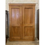 An Edwardian ash linen press, the plain cornice over two panelled doors enclosing four slides, two