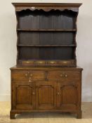 An 18th century country oak dresser of small proportions, the projecting cornice over three plate