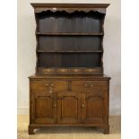 An 18th century country oak dresser of small proportions, the projecting cornice over three plate