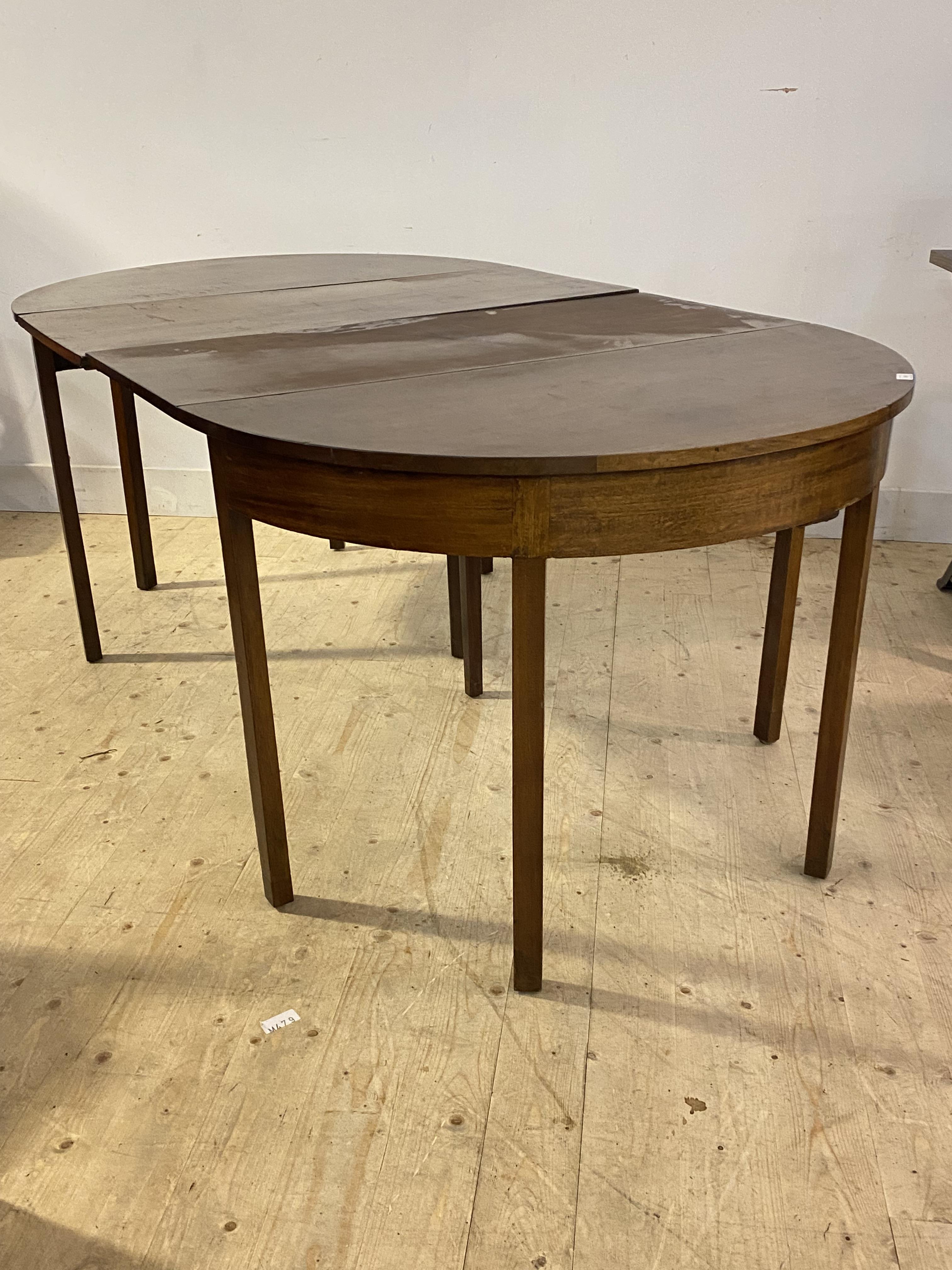 A Georgian mahogany drop leaf 'D' end dining table, the oval top raised on square section supports