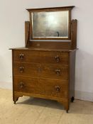 An Art Nouveau period oak dressing chest, with swing mirror over three graduated drawers having