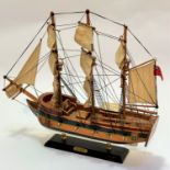 A treen model of HMS Bounty, raised on hardwood stand with brass mounts, (44 x 52)