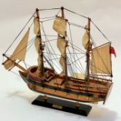 A treen model of HMS Bounty, raised on hardwood stand with brass mounts, (44 x 52)