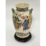 A Japanese pottery glazed twin handled baluster vase decorated with scenes of scholars with cherry