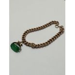 A 9ct gold curb link bracelet with clip fastening, mounted with green stone revolving 9ct gold seal,