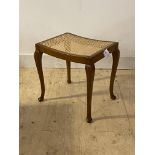 An early 20th century stained beech stool, with cane seat panel, standing on cabriole supports,