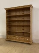 A Victorian pine open shelf unit, with four adjustable shelves over five drawers, raised on later