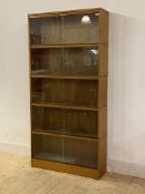 A mid century oak five height stacking bookcase, each section with two glazed sliding doors, stamped