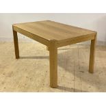 A contemporary light oak extending dining table, one end pulling out to accommodate two additional