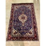 A Persian hand knotted rug, the busy blue field centred by an ivory medallion and bordered 133cm x