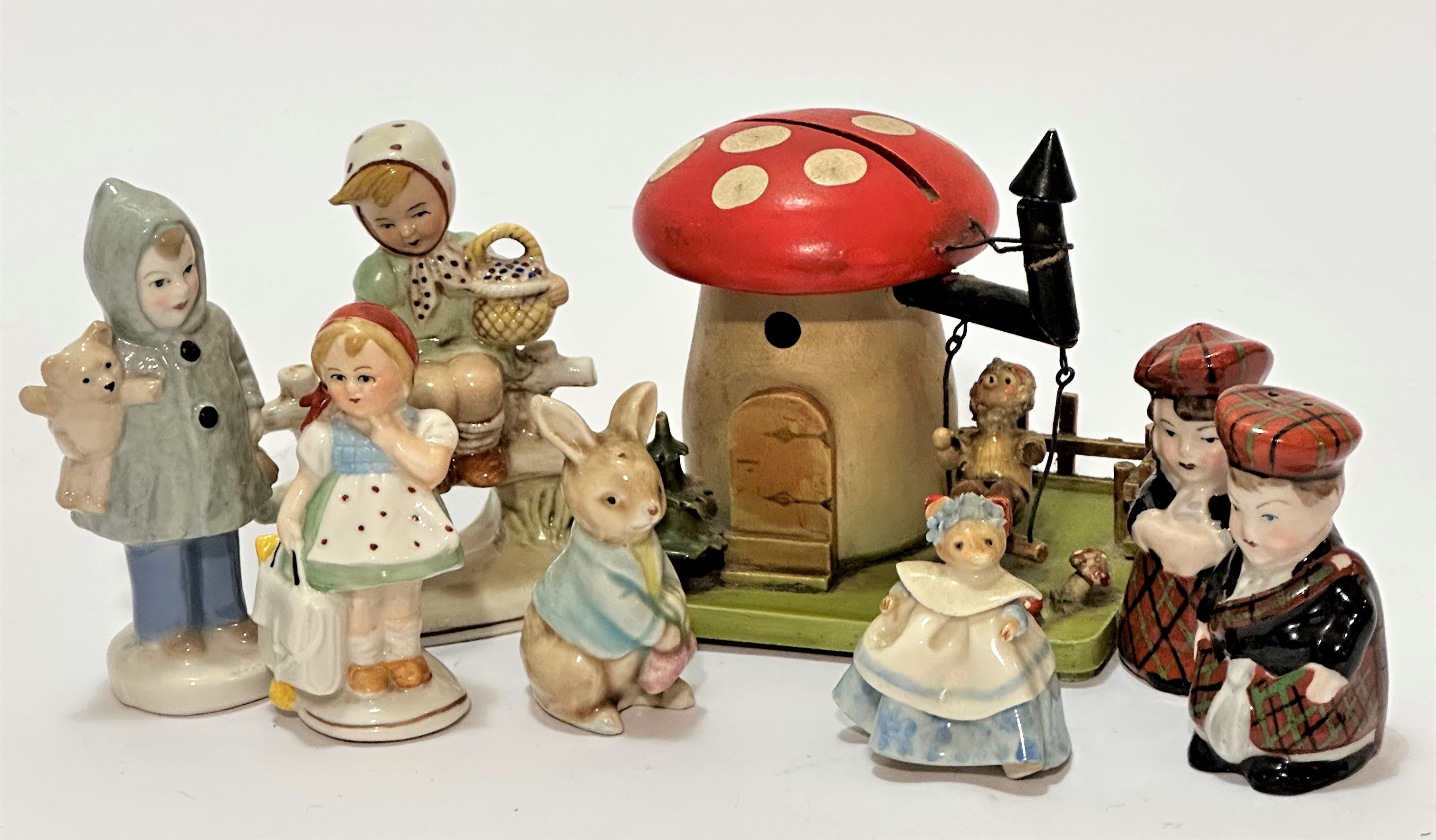 A treen figure on swing under a mushroom moneybox with picket style fence, some losses to paint