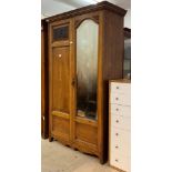 An Edwardian oak wardrobe, the cornice over two doors, one with arched mirror with bevelled edge,