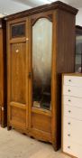 An Edwardian oak wardrobe, the cornice over two doors, one with arched mirror with bevelled edge,