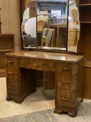 A 1920s walnut dressing table, the triple swing mirror back over one long and four short graduated