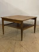 A mid century teak lamp table, the square top over slatted under tier, raised on square tapered