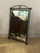 A cast and wrought metal wall hanging mirror, the bevelled plate enclosed by a frame finished in a