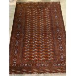 A hand knotted bokhara rug, the red field with four rows of guls framed within a multi line